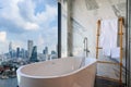 White bathtub near the window, overlooking the cityscape, building landscape outside scenery. Luxury master bathroom interior Royalty Free Stock Photo