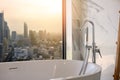 White bathtub near the window, overlooking the cityscape, building landscape outside scenery. Luxury master bathroom interior Royalty Free Stock Photo