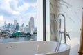 White bathtub near the window, overlooking the cityscape, building landscape outside scenery. Luxury master bathroom interior Royalty Free Stock Photo