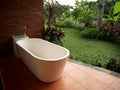 white bathtub and open room brown tiles grass trees landscape