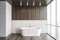 White bathtub on wooden floor in bathroom near window, white wooden design Royalty Free Stock Photo