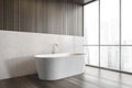 White bathtub on wooden floor in bathroom near window, white wooden design Royalty Free Stock Photo