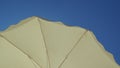 White beach umbrella. View from below. Relaxing context. Summer holidays by the sea. General contest and location