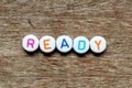 White bead with letter in word ready on wood background