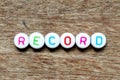 White bead with letter in word record on wood background