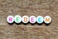White bead with letter in word redeem on wood background