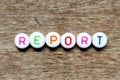 White bead with letter in word report on wood background