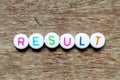 White bead with letter in word result on wood background