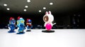 A white bear with a pink candy on a dark theater stage with no one tells the robot guards wearing blue helmets to go down.