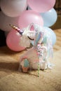 White beautiful unicorn against the background of balls with tasty gingerbread in the form of a unicorn and meringue on a stick