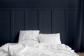 White bed linen on a mattress in a midnight blue bedroom