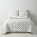 White bed setup featuring a quilted comforter and four matching pillows. The