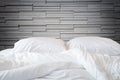 White bedding sheets and pillow on natural stone wall room background, Messy bed concept Royalty Free Stock Photo