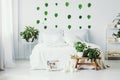 White bedroom interior with king size bed, urban jungle and green leafs on the wall