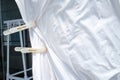 White bedsheet drying in the sun, White clothespins, White coat hanger in house, Wrinkled texture, Abstract background, Close up