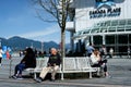 white bench benches around a blue bare tree people went out into nature sunny day sit rest tourists near Canada Place in Royalty Free Stock Photo