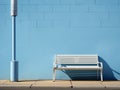 a white bench next to a blue wall