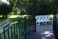 white bench for relaxing in the park and the path to it through the bridge Royalty Free Stock Photo