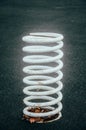 White big, giant spring on a black background. White very large and thick metal spring sticks out of the ground, attached to the Royalty Free Stock Photo