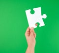 white big puzzle in female hand on green background Royalty Free Stock Photo