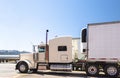 White big rig classic powerful semi truck with refrigerated semi trailer standing on truck stop parking lot in Utah