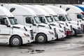 White big rig pro semi truck tractors with semi trailers standing in row on the industrial parking lot waiting for the next loads Royalty Free Stock Photo