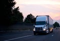 White big rig semi truck with dry van trailer driving on evening Royalty Free Stock Photo