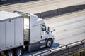 White big rig semi truck with low cab transporting cargo in dry van semi trailer running on the overpass highway intersection