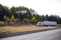 White big rig semi truck tractor with reefer trailer going out o