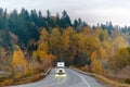 White big rig semi truck transporting goods on the winding autumn wet raining road at twilight Royalty Free Stock Photo