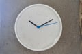 White big wall clock with blue second hand on rough cement wall