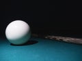 White billiard ball a cue on a table. Black background