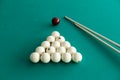 White billiard balls for Russian billiards, in a triangle and cue sticks on the table. Royalty Free Stock Photo