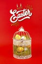 White bird cage with Easter eggs in it on a red background Royalty Free Stock Photo
