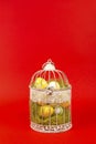 White bird cage with Easter eggs in it on a red background Royalty Free Stock Photo