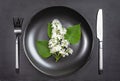 White bird cherry blooming branch on black plate with cutlery on black shale serving board. Season allergy concept. Royalty Free Stock Photo