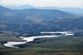 White birds perched on a grassy hilltop overlooking a serene river below Royalty Free Stock Photo