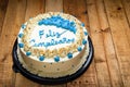White Birthday Cake Decorated With Blue Cream Cheese Flowers And \"happy Birthday\" Text In Spanish.