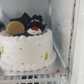 white birthday cake topped with chocolate biscuits and strawberries in the refrigerator