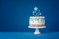 White birthday drip cake with teal ganache, star toppers and fun candles over dark blue background Royalty Free Stock Photo