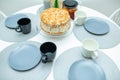 White biscuit cake cut on a stand on a serving table. Around the cake lay out plates with cups and tea Royalty Free Stock Photo