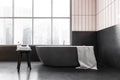 White and black bathroom with bathtub near window, towel and table with gels