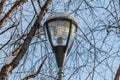 A white and black beautiful street lighting lantern against the blue sky background with white snow and icicle and with