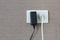 White and black cable plugged in a white electric outlet mounted Royalty Free Stock Photo