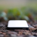 A white and black device is sitting on a leafy ground, AI