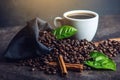 White black espresso Cup with pile of coffee beans and green leaves in bag on dark background Royalty Free Stock Photo