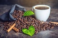 White black espresso Cup with pile of coffee beans and green leaves in bag on dark background Royalty Free Stock Photo