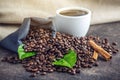 White black espresso Cup with a pile of coffee beans and green leaves in bag on white linen background Royalty Free Stock Photo