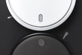 White and black modern robot vacuum cleaner on black background flat lay. New technologies, quick house cleaning automatic robot