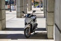 A white and black motor scooter parked on a sidewalk surrounded by concrete pillars in downtown Atlanta